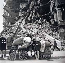 Un groupe d'enfants avec des ballots sur un chariot devant des décombres (Robert Capa,  août 1945)